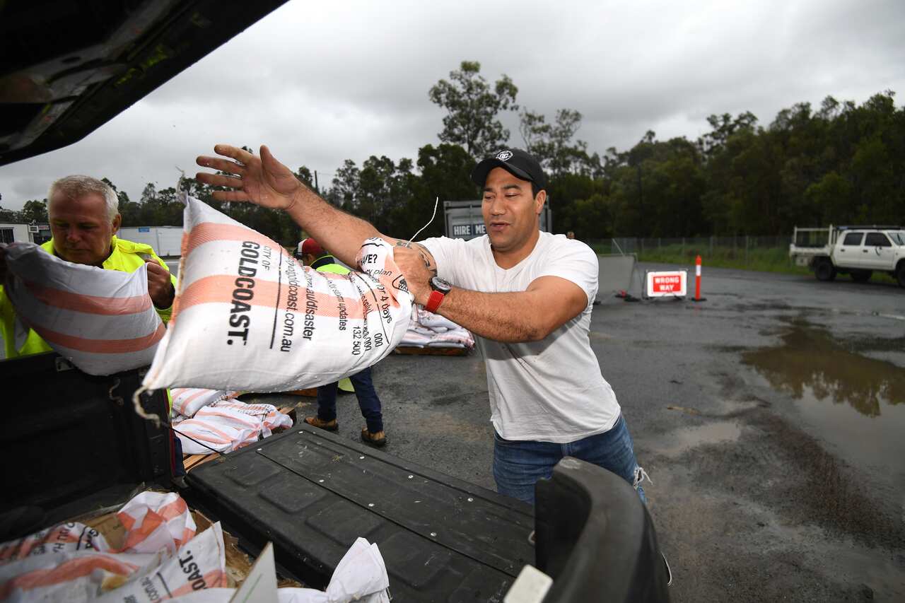 A man loads up sandbags to his car at Pimpama on the Gold Coast, Sunday, December 13, 2020. Heavy rainfall, high winds and flooding is forecasted for the region and into northern NSW. (AAP Image/Dan Peled) NO ARCHIVING
