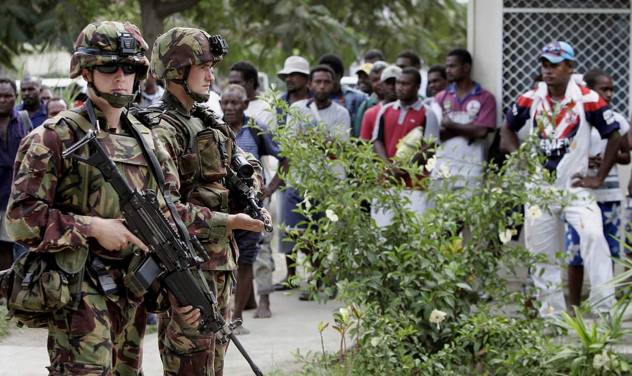 New Zealand troops stand guard over a crowd of more than 200 Solomon Islanders