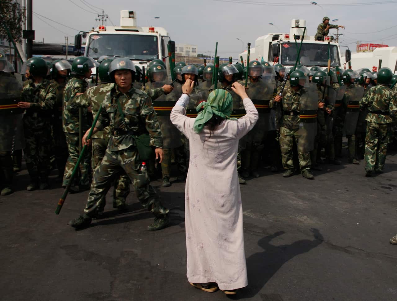 A Uighur woman protests before a group of paramilitary police  in China's Xinjiang region.