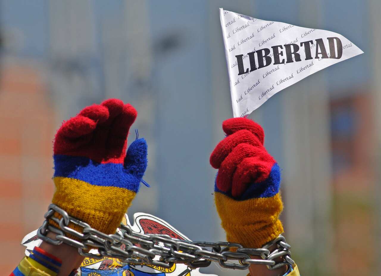 A protester, in chains, holds a flag that reads in Spanish: "Freedom" during a march against kidnapping in Medellin, Colombia, Friday, Nov. 28, 2008.