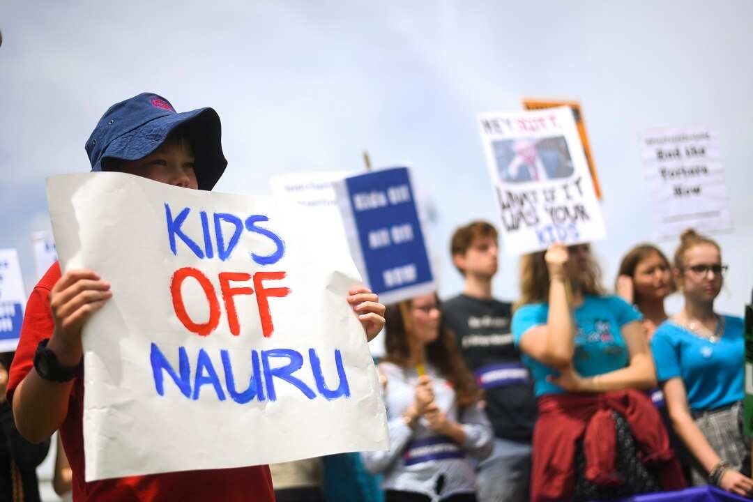 Protesters hold up signs during a rally demanding the resettlement of kids held on Nauru outside Parliament House in Canberra, Tuesday, November 27, 2018. (AAP Image/Lukas Coch) NO ARCHIVING