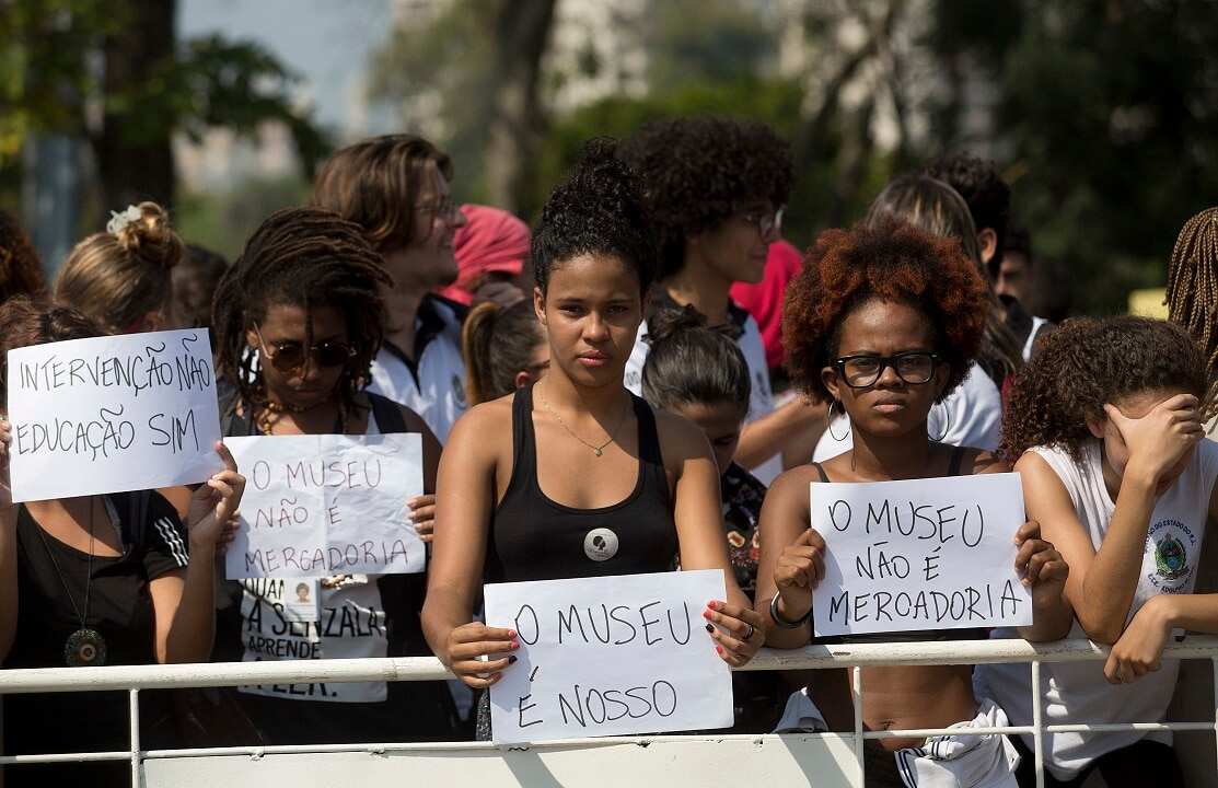 Protesters hold signs that read: "The museum is ours" and the "The museum is not merchandise."