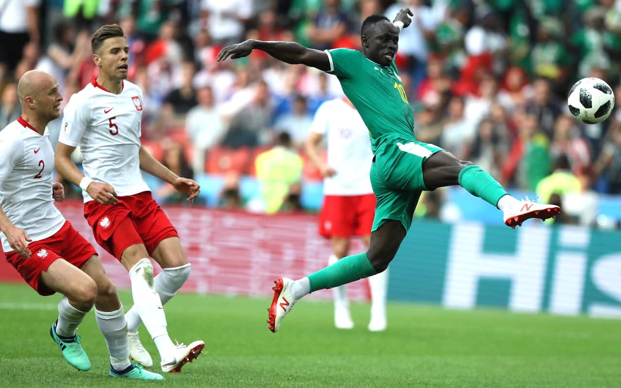 Sadio Mane of Senegal controls the ball under pressure of Michal Pazdanand Jan Bednarek of Poland 