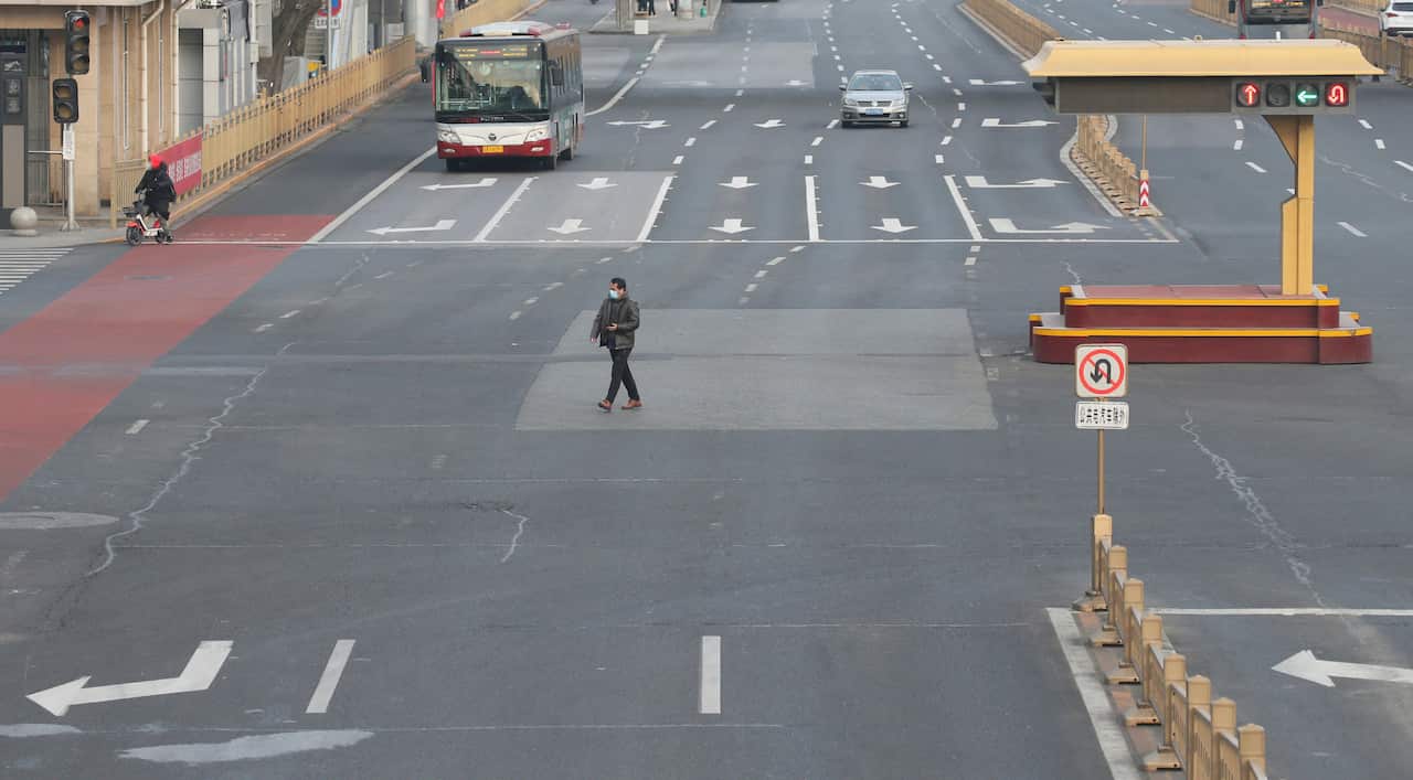 A man crosses an empty street in Beijing during the COVID-19 pandemic.