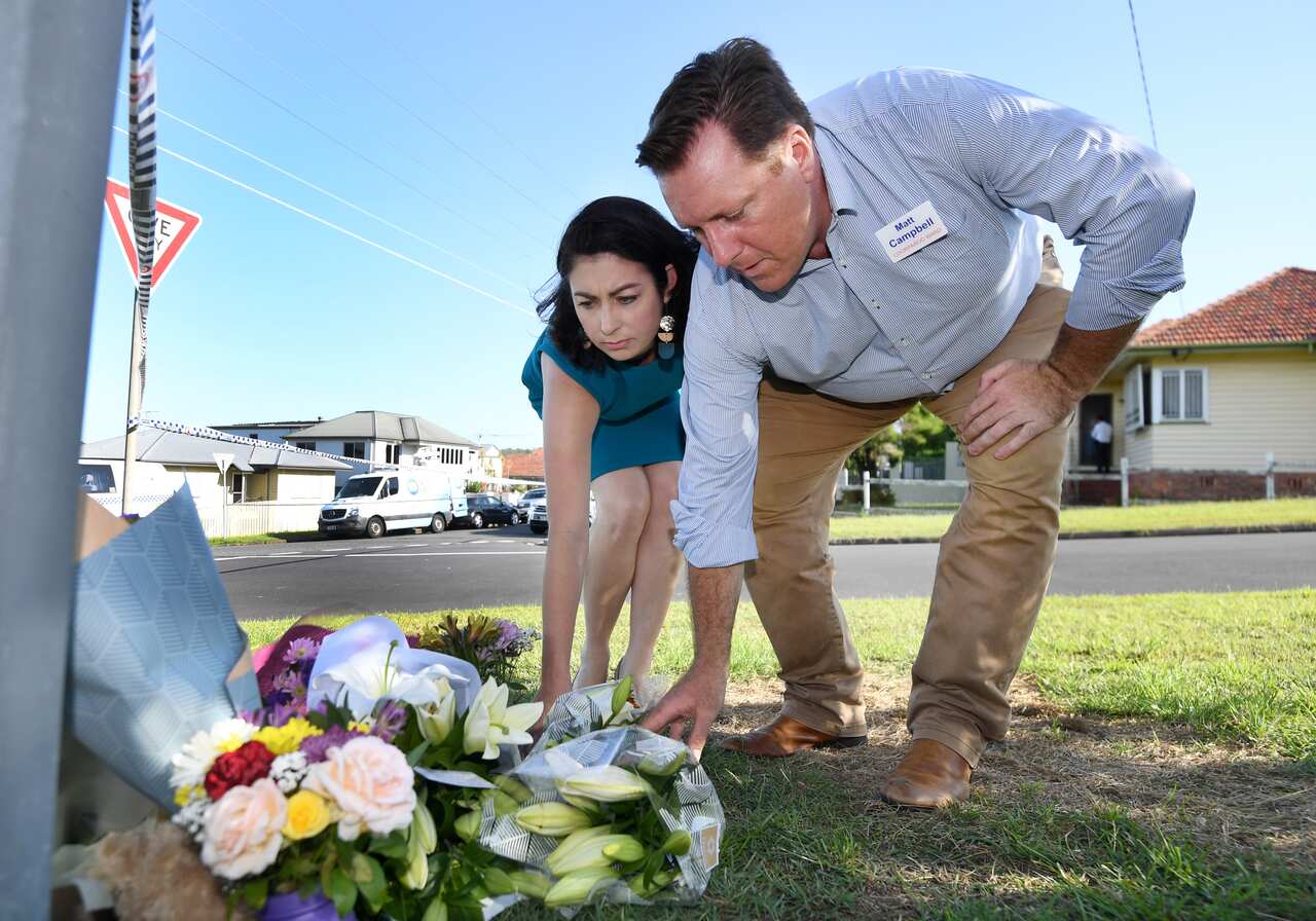 Federal member for Griffith Terri Butler and Labor's candidate for Brisbane City council Matt Campbell place flowers near the scene of the fatal car fire. 