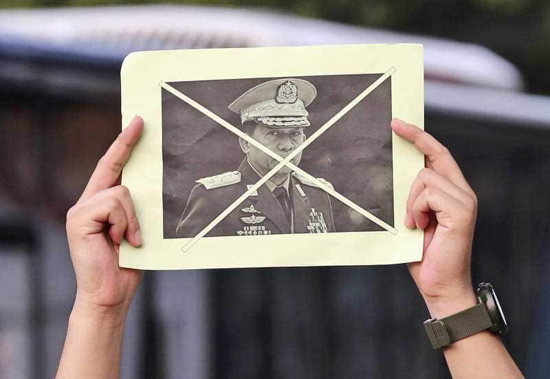 An activist holds up a defaced portrait of Myanmar's Commander-in-Chief Senior General Min Aung Hlaing during a rally against the military coup in Jakarta
