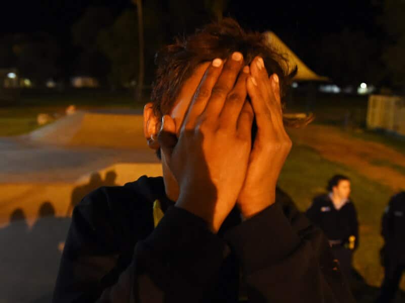 An Aboriginal youth covers his face at a skate park in Bourke, NSW
