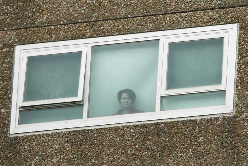 A resident looks out a window in public housing towers in North Melbourne, Sunday, July 5, 2020