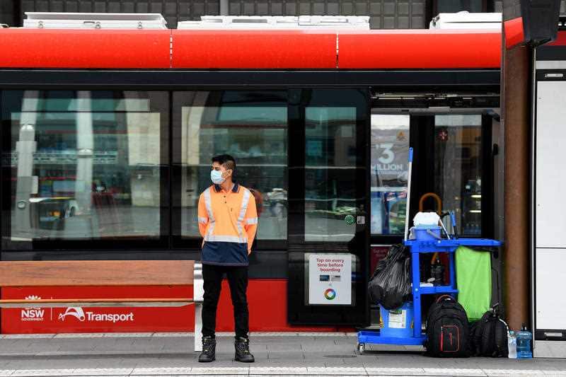 A cleaner is seen waiting for the next arriving tram at the Circular Quay light rail station in Sydney, Monday, March 30, 2020