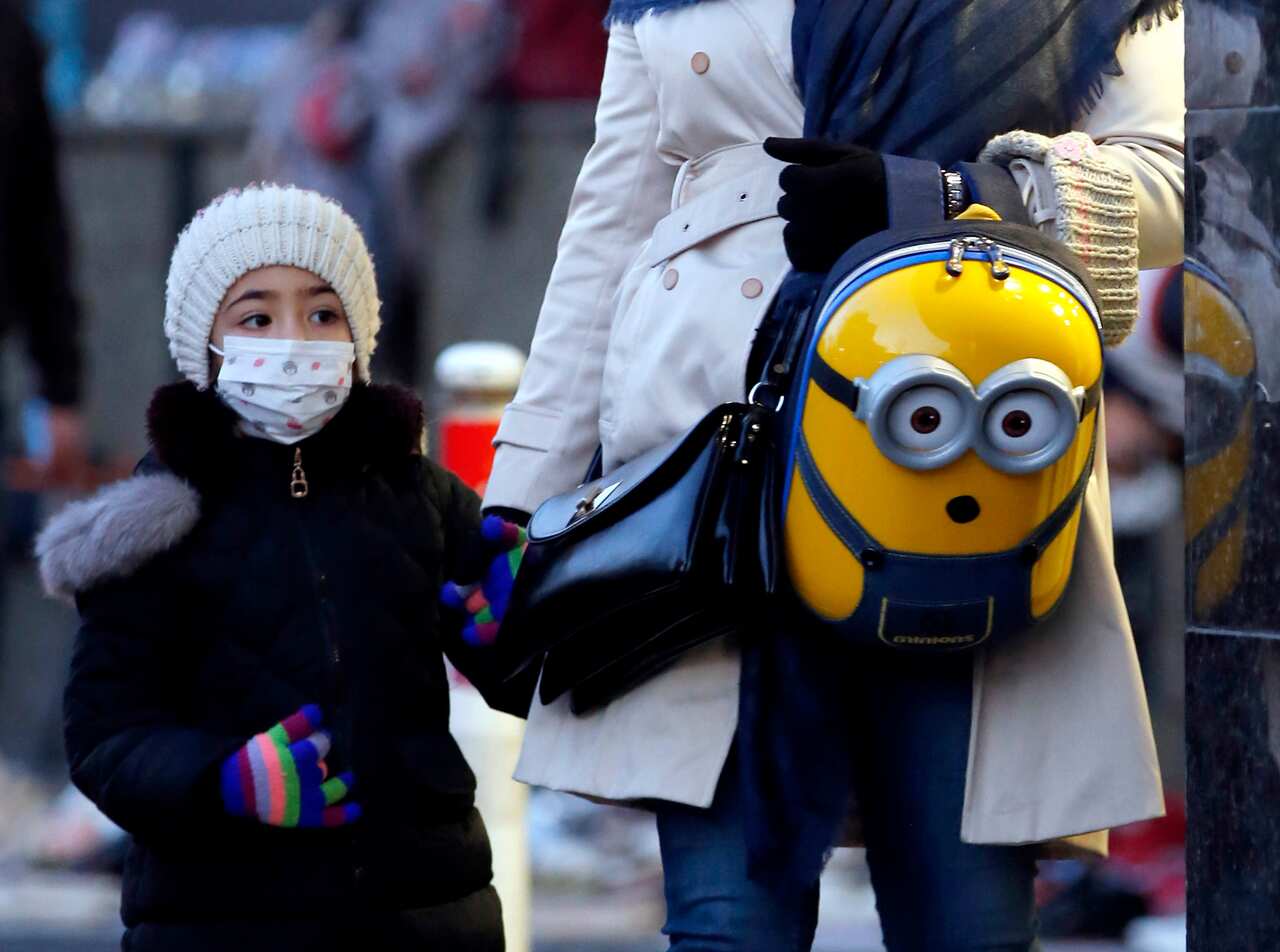 An Iranian woman and her child wearing face masks walk on a street of Tehran, Iran.