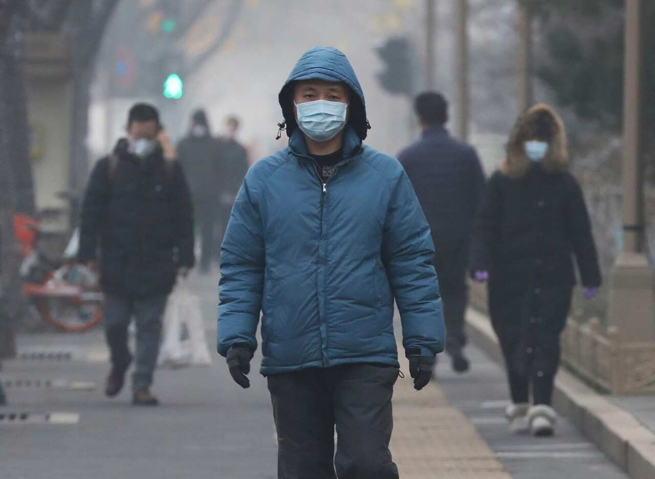 People wear mask at a street in Beijing on Thursday.