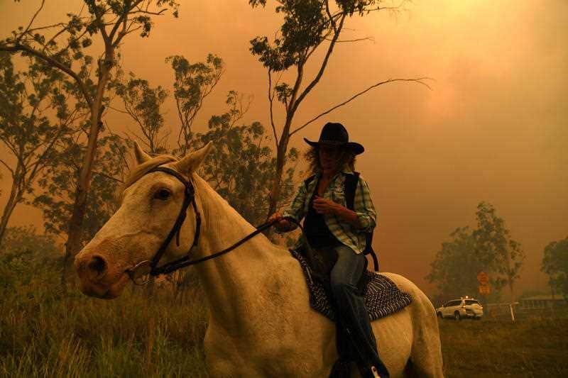 Rhonda Anderson evacuates herself and her horse to safety near Mount Larcom, Queensland, Wednesday, November 28, 2018.