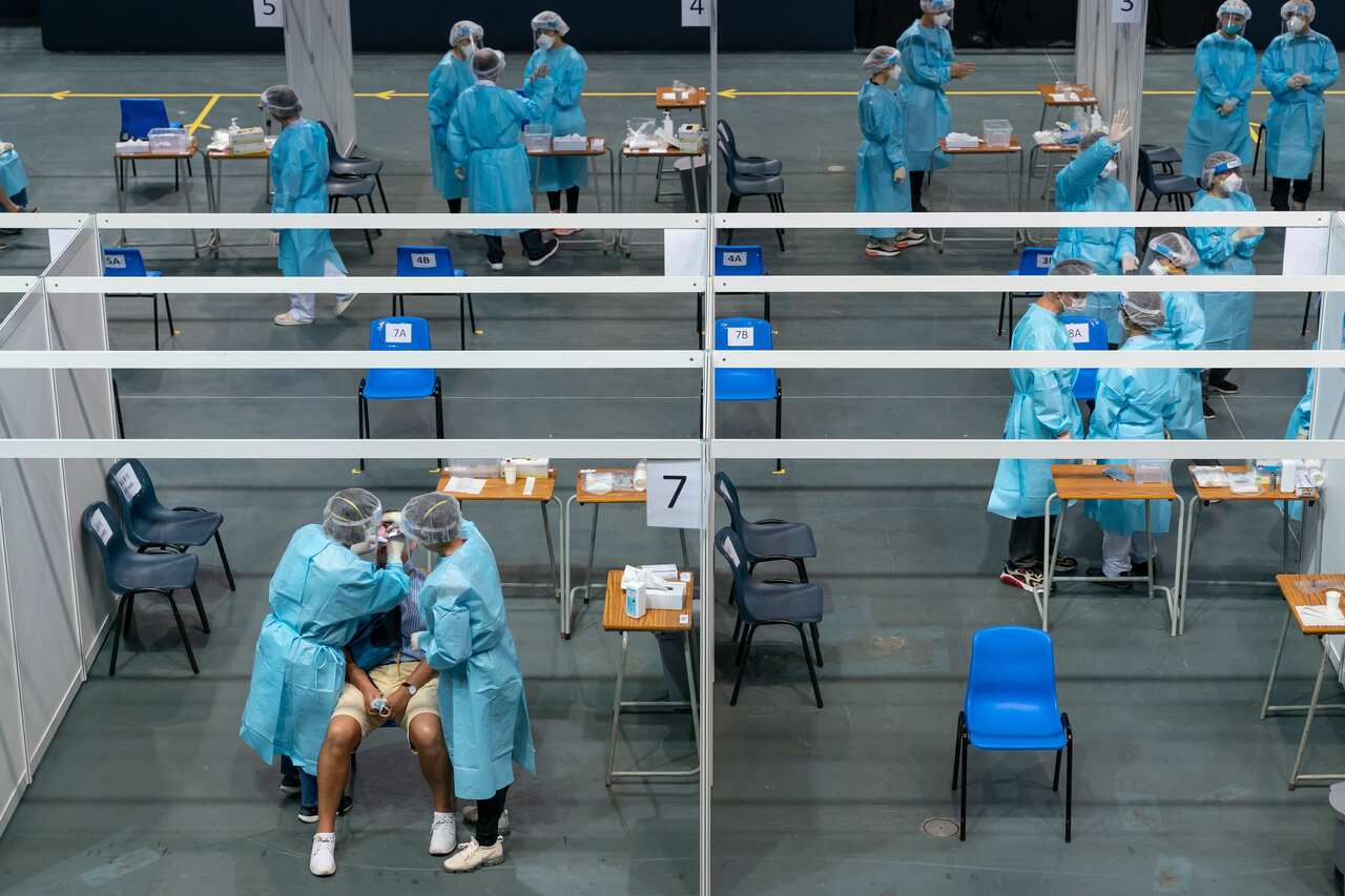 Medical professionals collect samples from a man at a makeshift COVID-19 testing site at Queen Elizabeth Stadium in Hong Kong on 1 September.