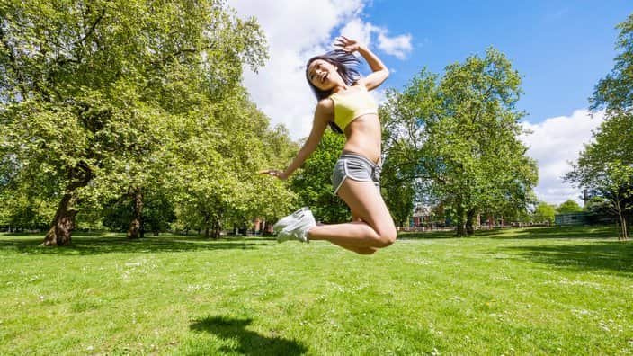 Full length of happy fit woman jumping in park