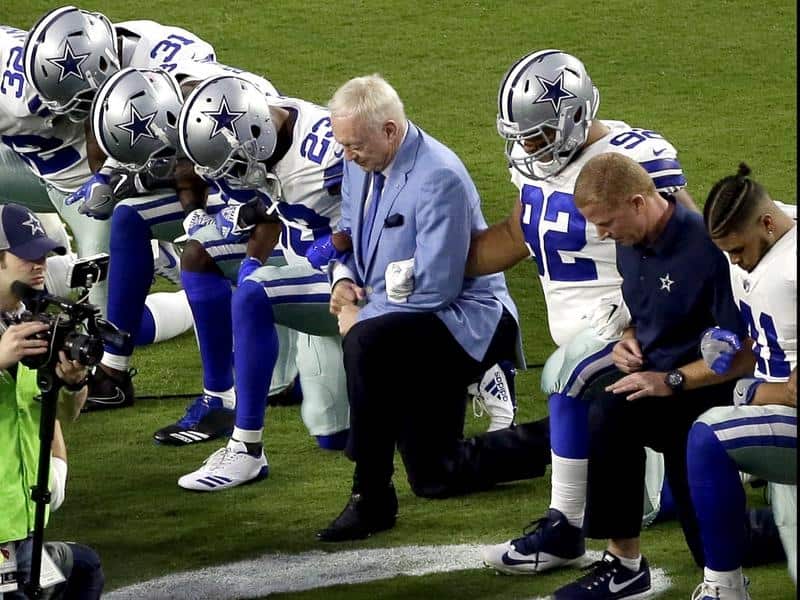 Dallas Cowboys owner Jerry Jones kneels with his players.