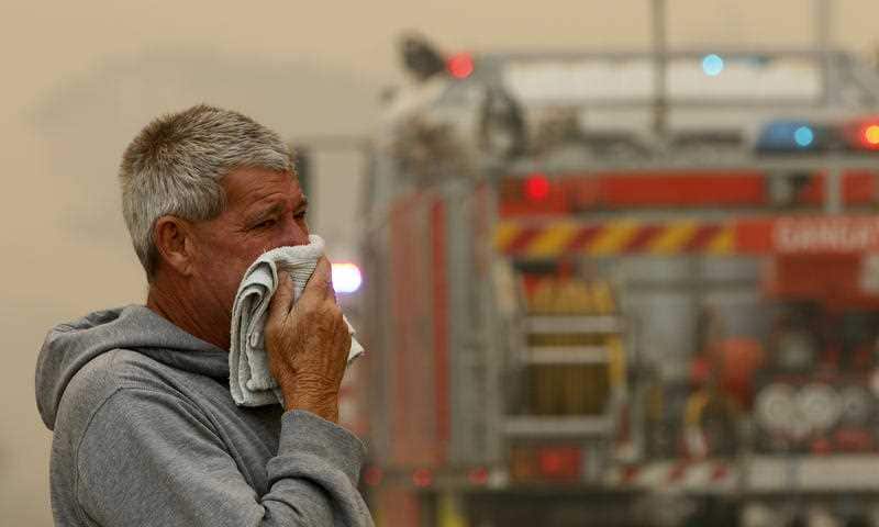 A resident watches the progress of bushfires near houses in Old Bar, NSW, Saturday, November 9, 2019