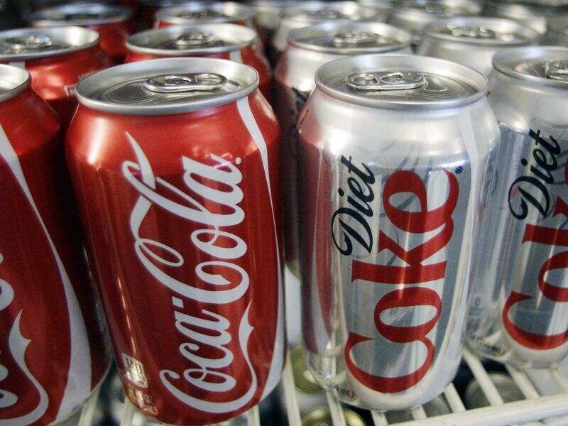 Cans of Coca-Cola and Diet Coke sit in a cooler