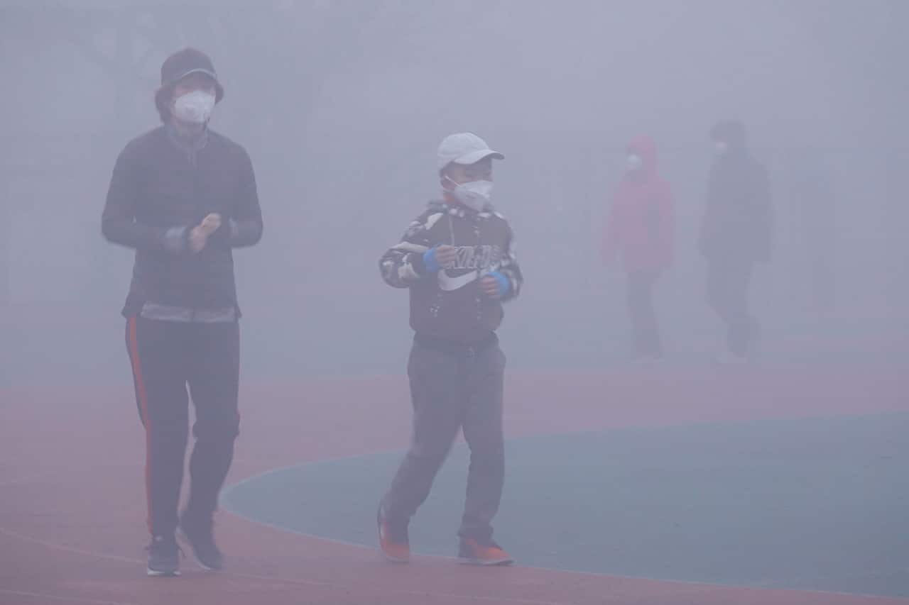 Pedestrians wearing face mask against air pollution walk on a road in heavy fog in Dalian city, northeast China's Liaoning province.