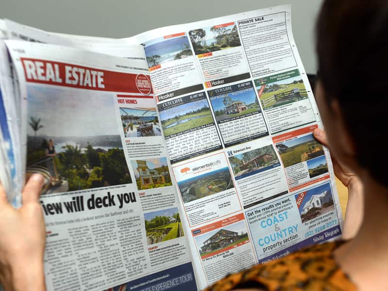 A woman looks at real estate advertising in a newspaper in Brisbane, Monday, Jan. 6, 2014. (AAP Image/Dan Peled) NO ARCHIVING