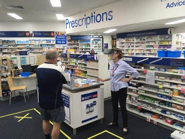 Uma funcionária da farmácia Manly Vale, em Sydney, usa um "escudo facial" enquanto atende aos clientes.