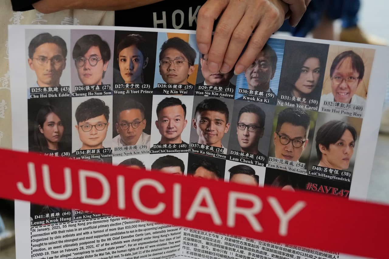 A supporter holds placard with the photos of some of the 47 pro-democracy defendants 