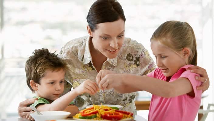 Mother Helping Children Prepare a Meal in kitchen