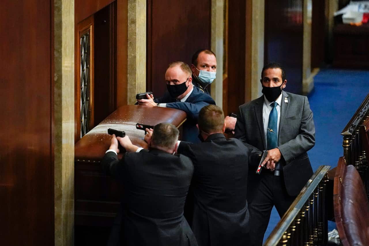 U.S. Capitol Police with guns drawn stand near a barricaded door as protesters try to break into the House Chamber at the U.S. Capitol on Wednesday, Jan. 6, 2021, in Washington. (AP Photo/Andrew Harnik)