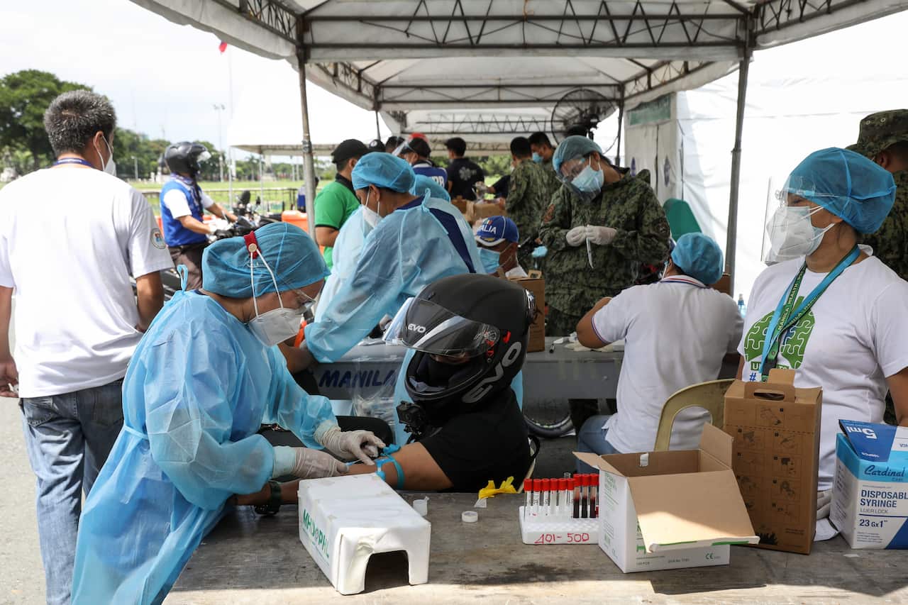 A health worker extracts blood from a patient at a drive-thru COVID-19 testing centre in Manilla.