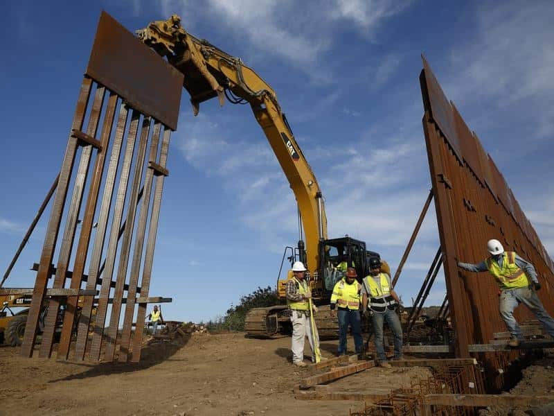 Construction crews install new border wall sections seen from Tijuana.