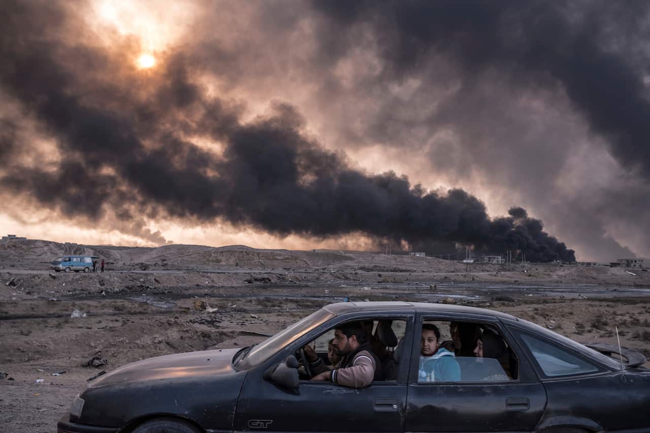 "Iraq's Battle To Reclaim Its Cities" shows a family flees the fighting in Mosul, Iraq's second-largest city, as oil fields burned in Qayyara, Iraq.