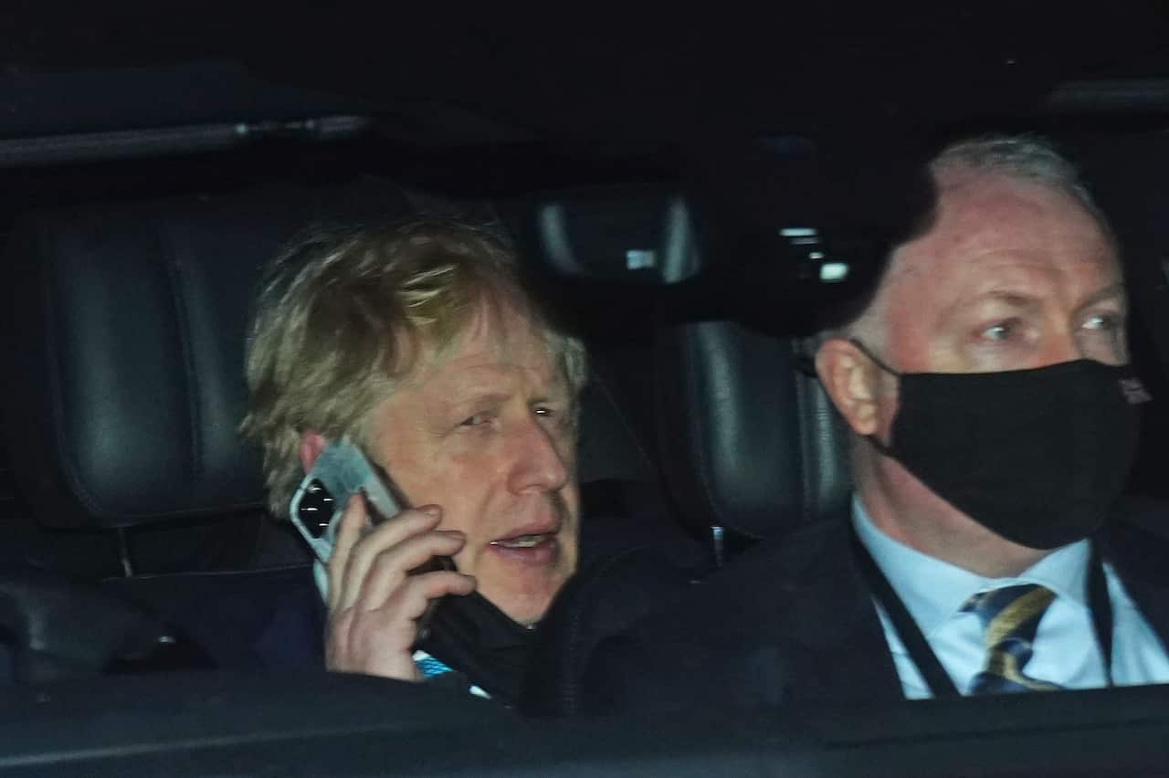 Prime Minister Boris Johnson (left) rides in the back seat of a government car while speaking on a mobile phone as he returns to Downing Street, London.