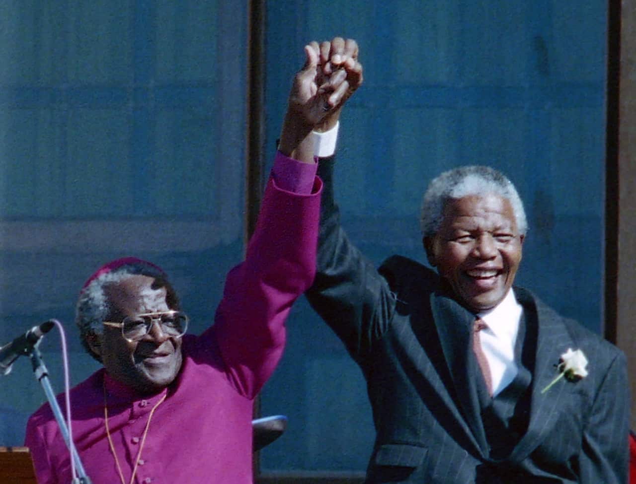 Former South African president Nelson Mandela holding hands with former Bishop Desmond Tutu