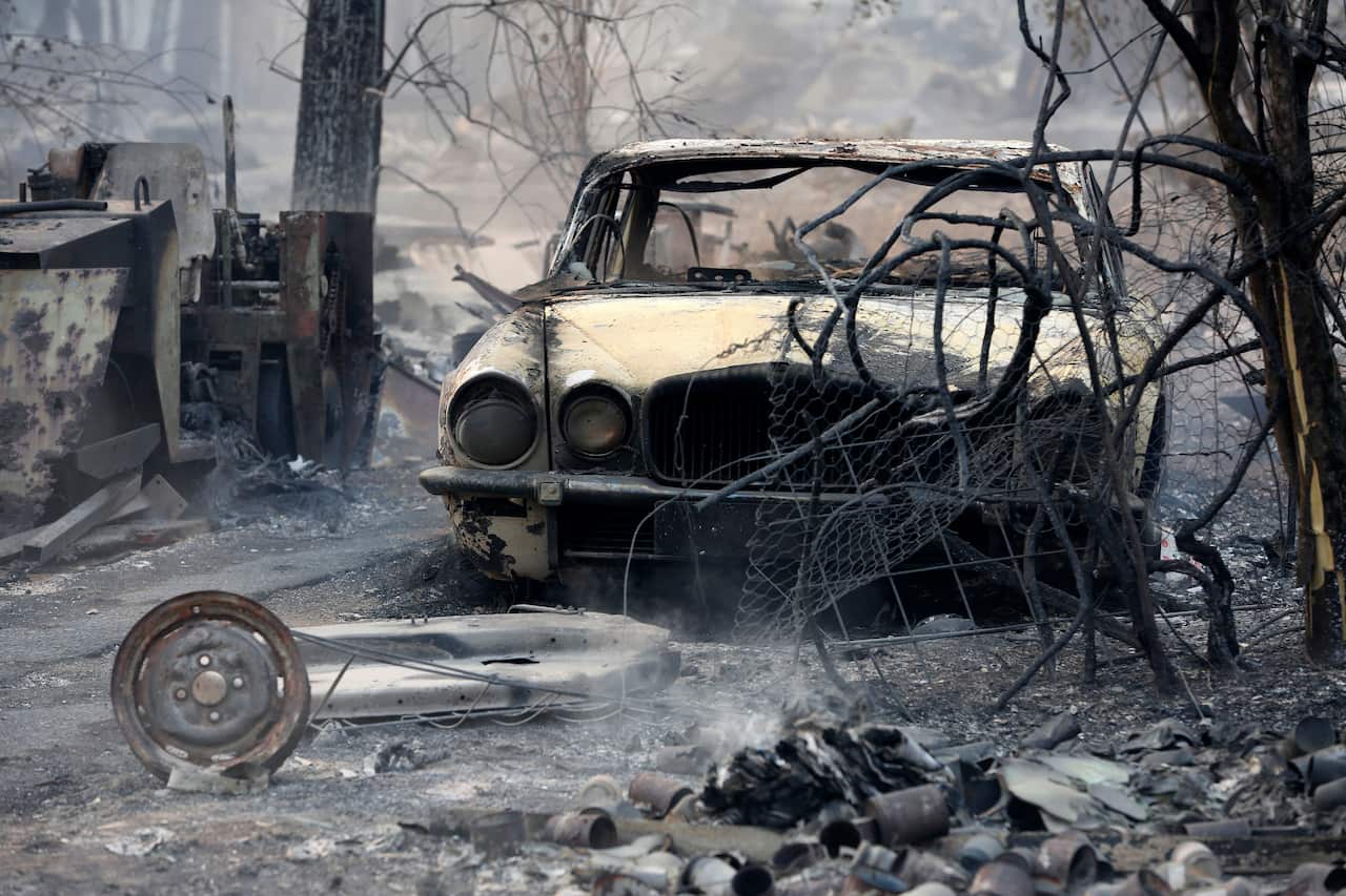 The burnt out shell of a vehicle sits in the ruins of a smouldering house.