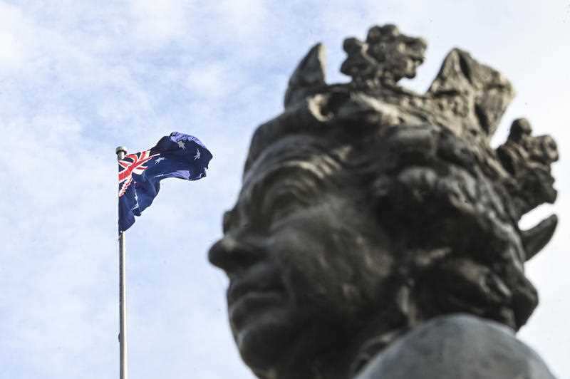 The Australian flag flies next to a statue of her Majesty the Queen Elizabeth II at Parliament House in Canberra, Monday, July 13, 2020. 