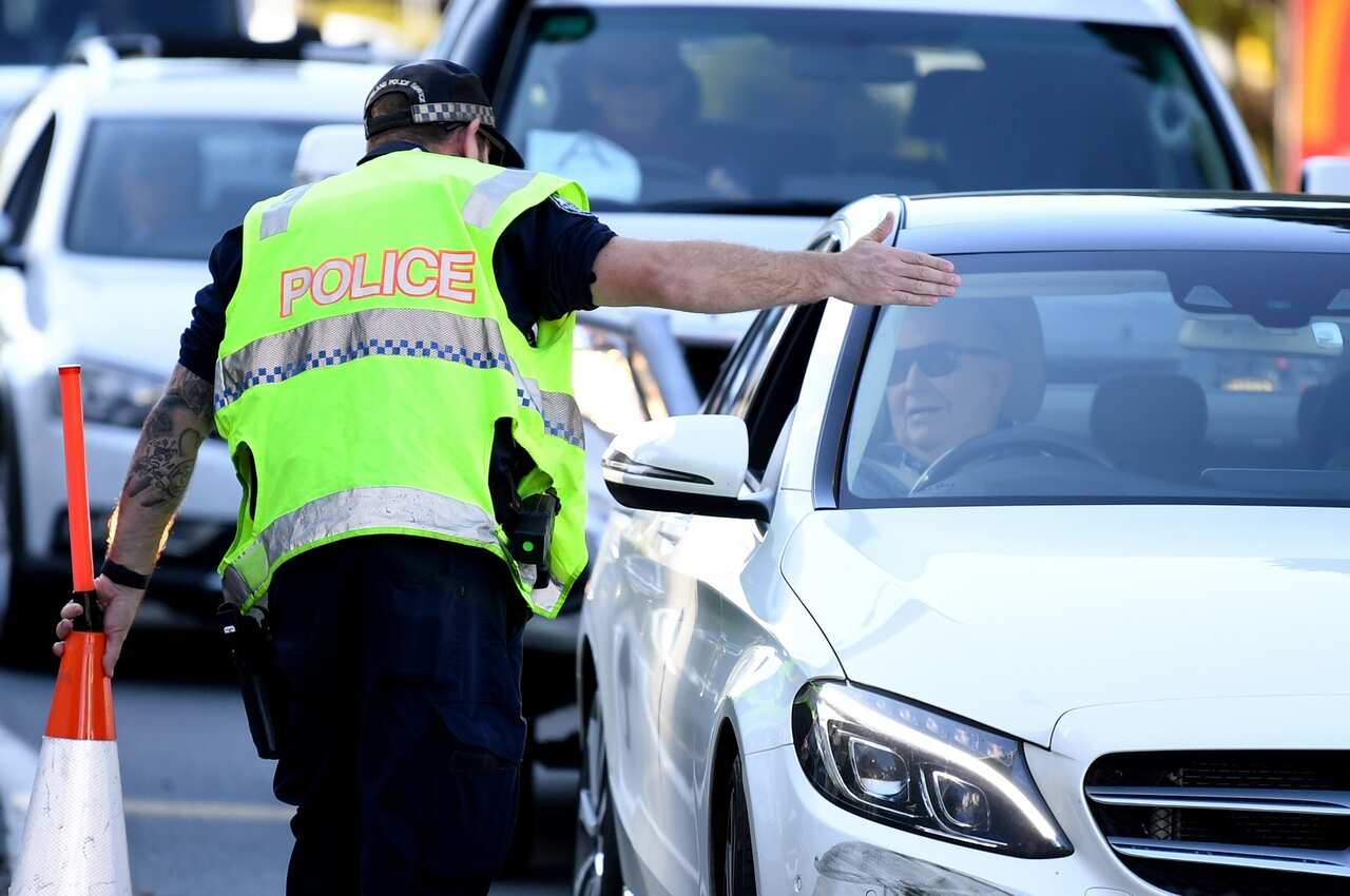 A police officer directs a car for further inspection at a check point on the Queensland-New South Wales border in Coolangatta on the Gold Coast.