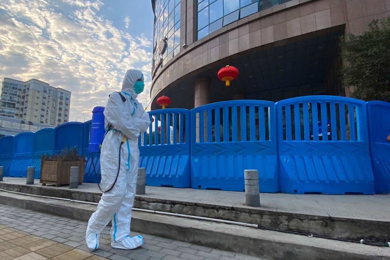 A worker in protectively overalls and disinfecting equipment walks outside the Wuhan Central Hospital