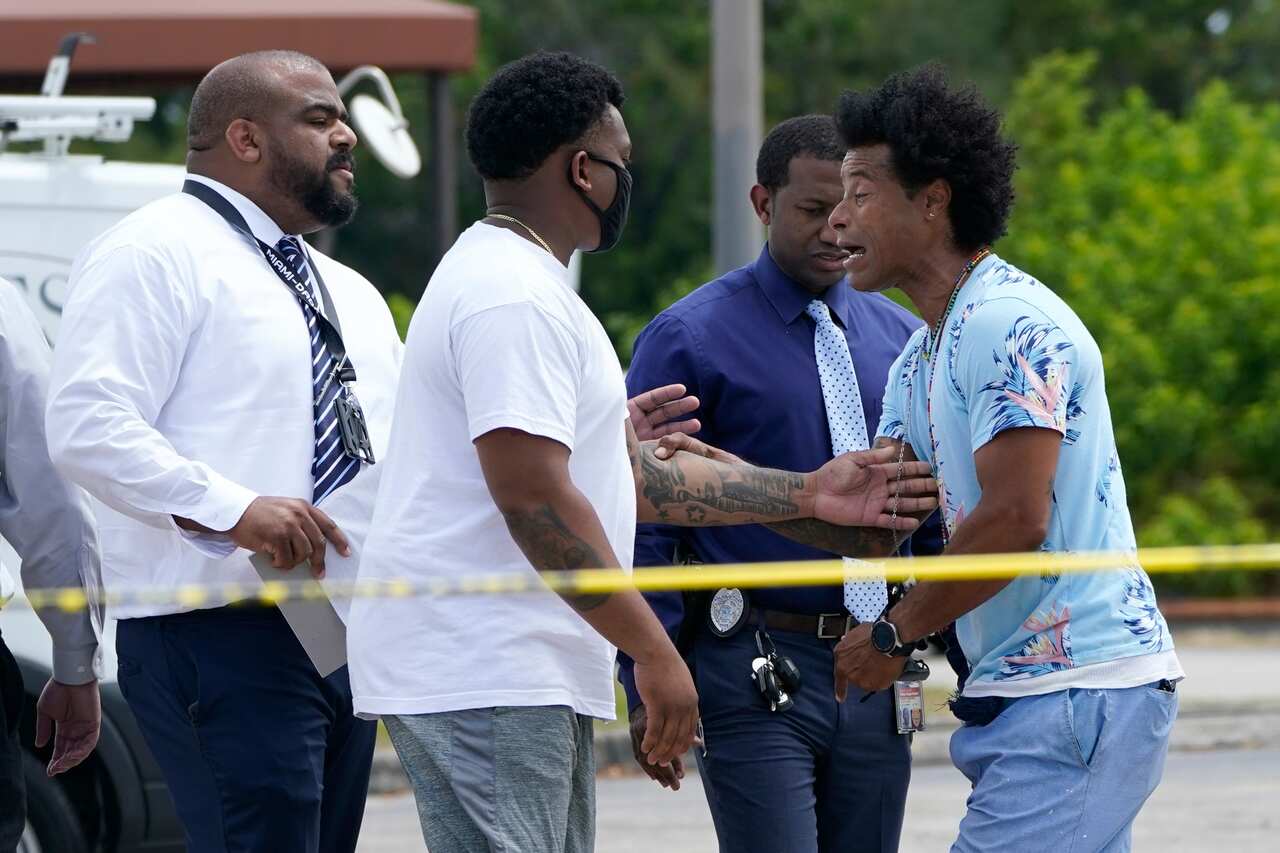 Clayton Dillard, right, talks with a police official, seeking information about a family member after the fatal shooting at near Hialeah, Florida.