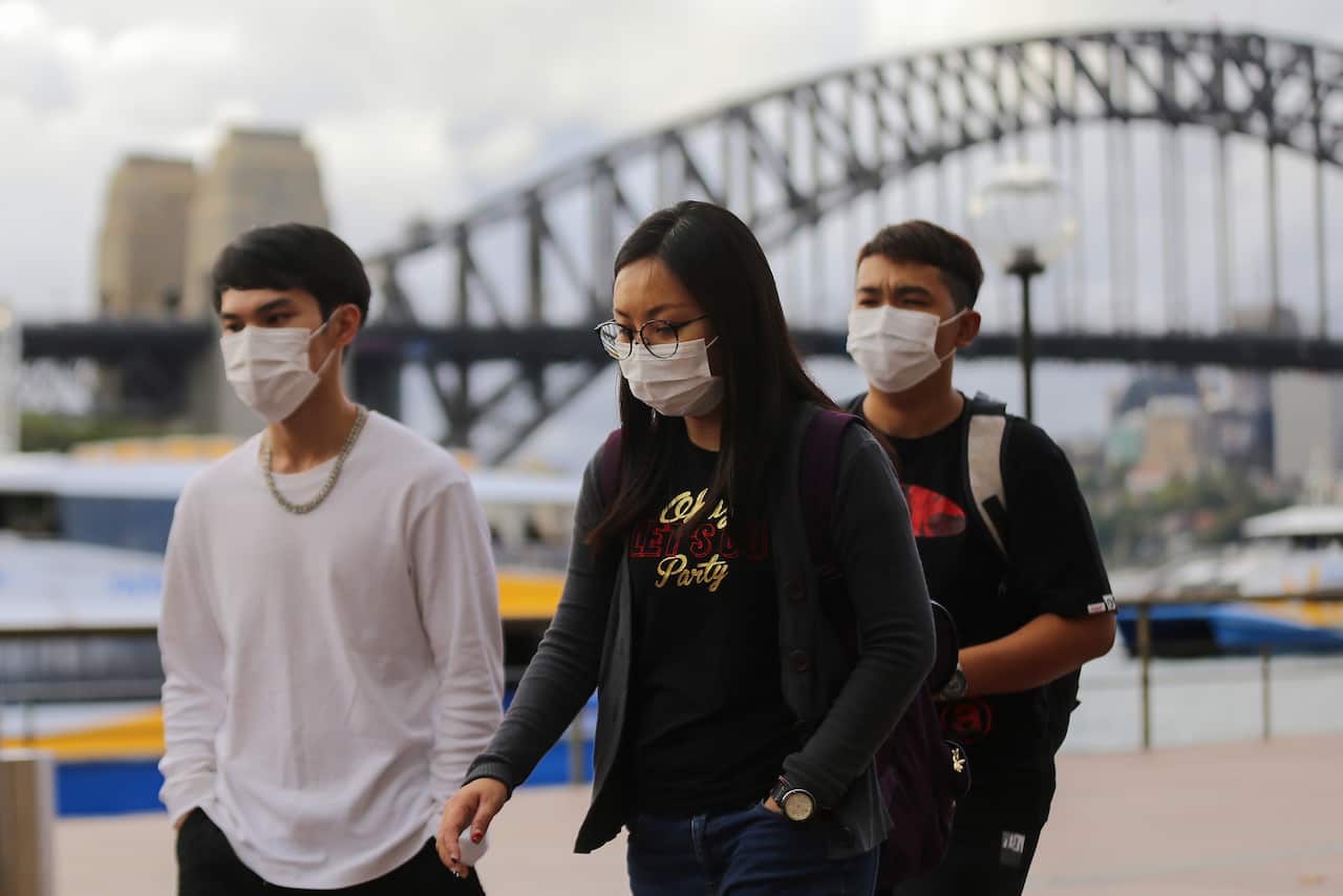 People wear face masks in front of the Sydney Harbour Bridge.