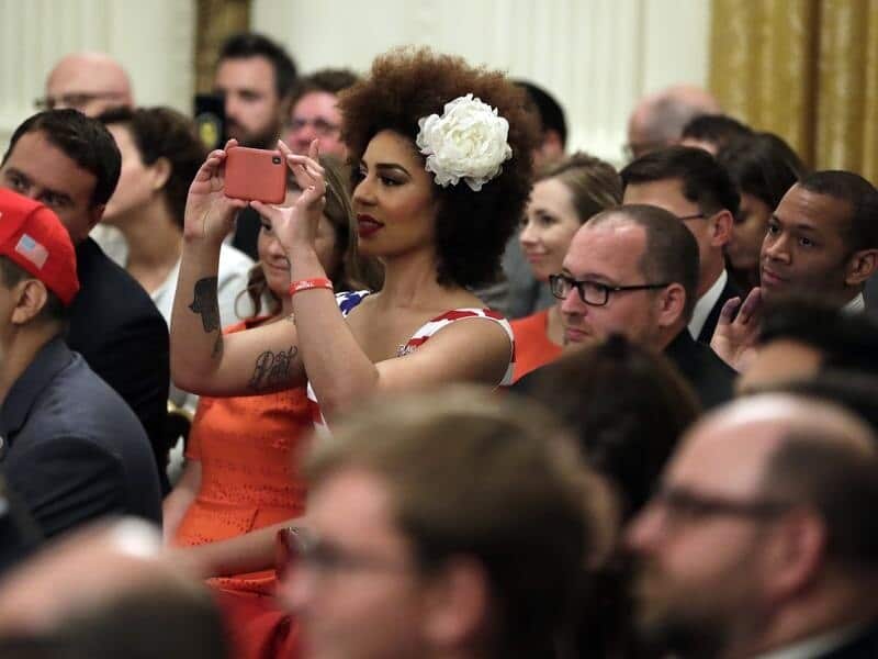 Invited guests take pictures of President Donald Trump