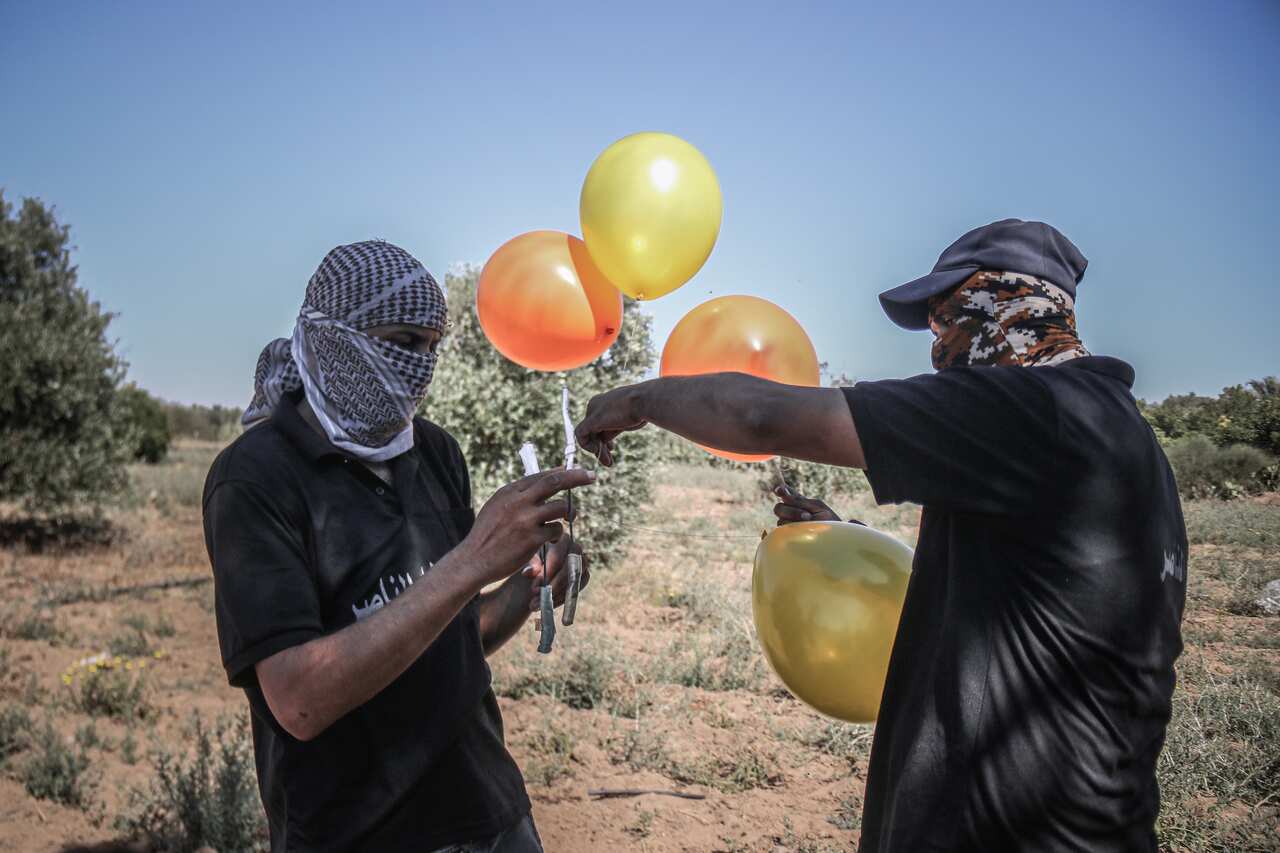 Masked supporters of the Al-Nasir Salah Al-Din Brigades prepare incendiary balloons east of Gaza city, to launch across the border fence towards Israel.