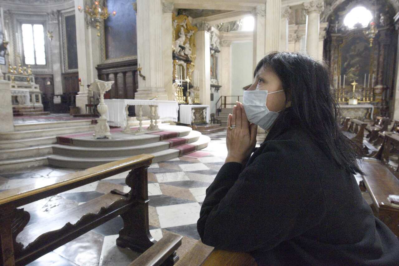 A worshipper prays with a mask on in Italy during the COVID-19 Crisis.