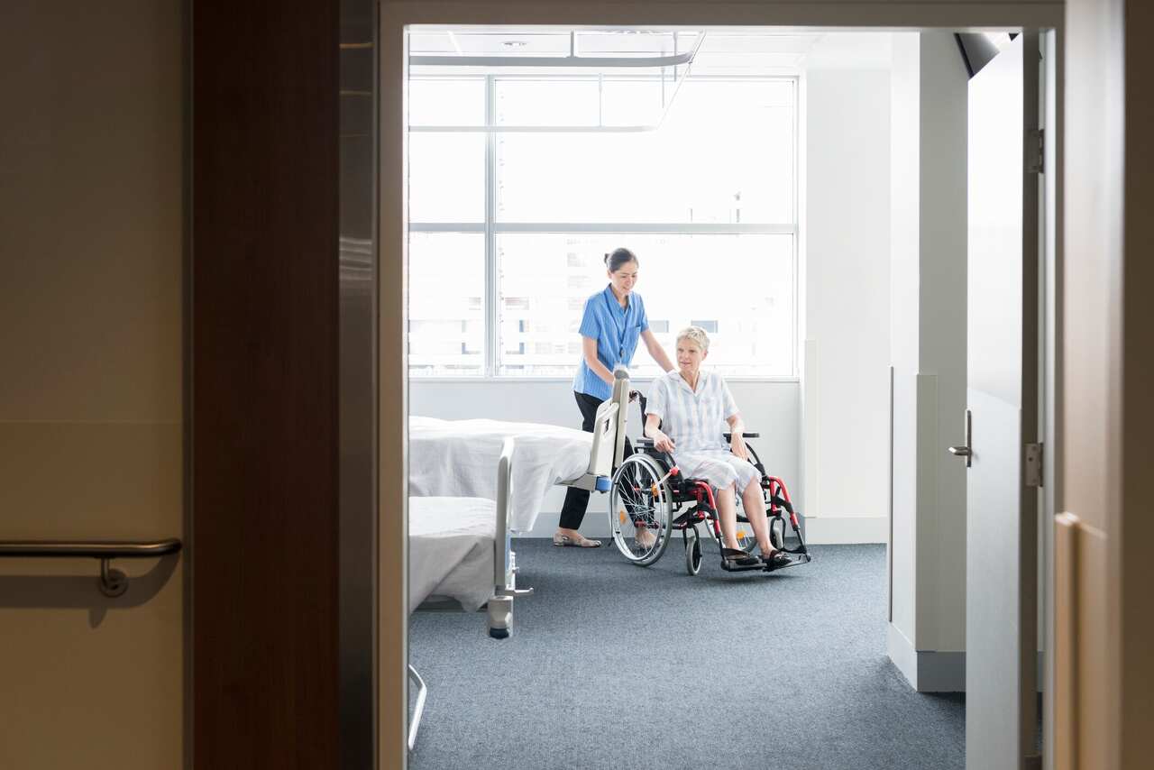 Senior woman in wheelchair with female nurse on the ward