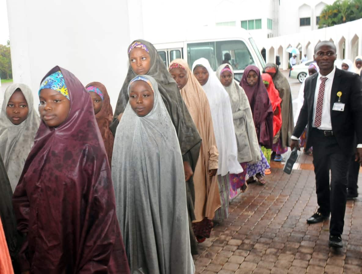 A group of the released Dapchi School Girls who were abducted by Boko Haram pass a security guard (R) as they arrive for a reception 