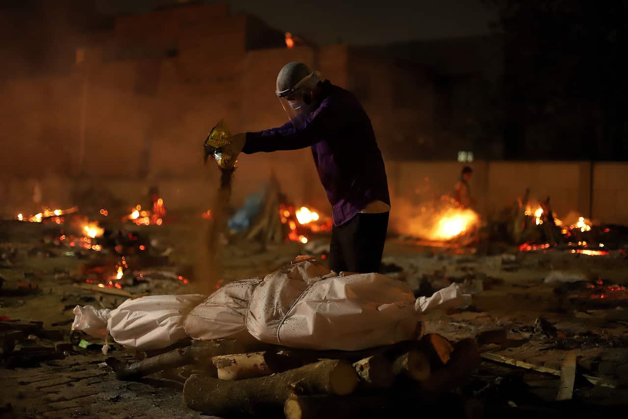 A man performs last funeral rites of a victim who died from COVID-19 at a cremation ground in New Delhi.