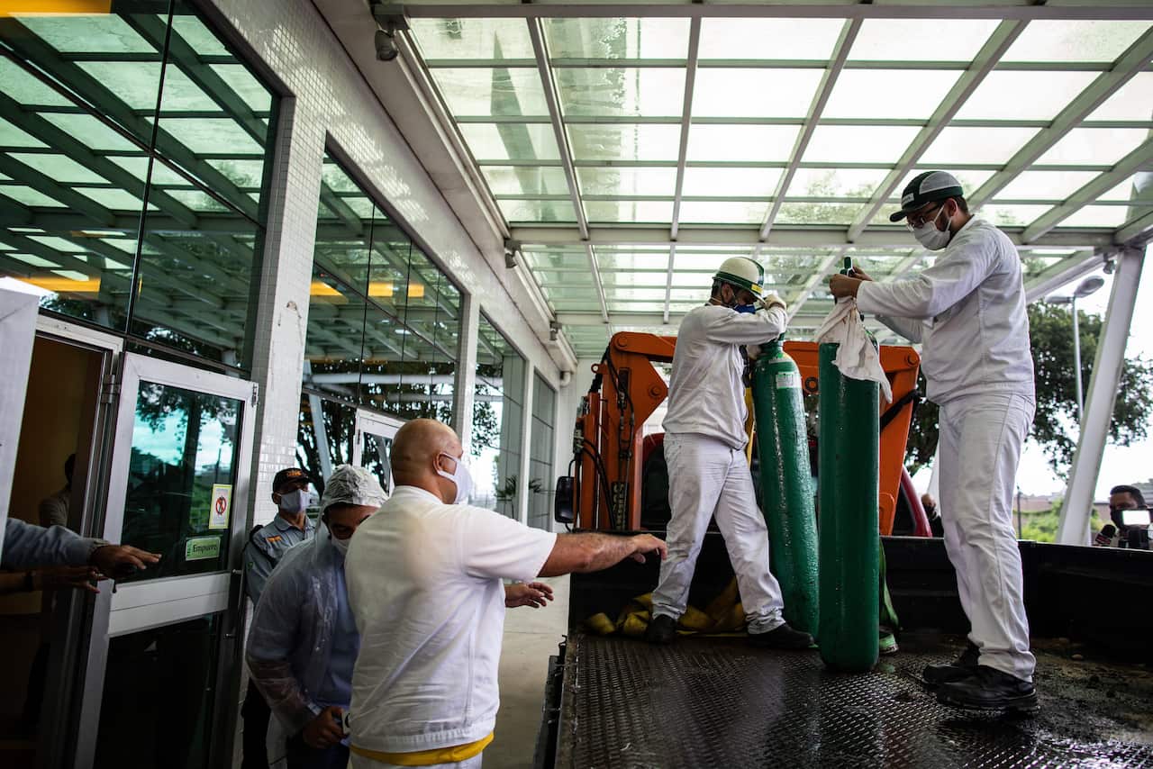 Workers carry oxygen cylinders at the Getulio Vargas University Hospital, in Manaus, Brazil, 14 January 2021.