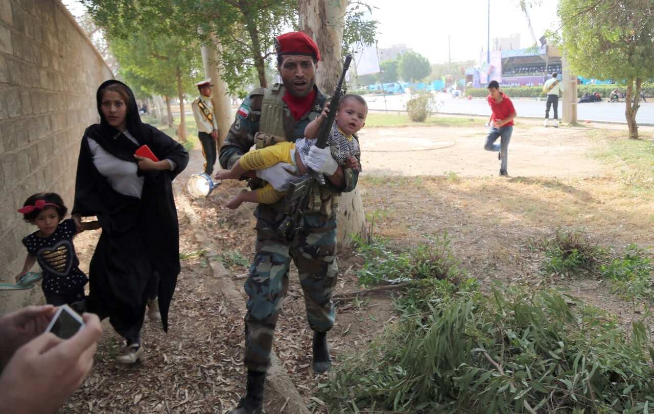 An Iranian soldiers carries a baby as he tries to save a family during a terror attack during a military parade in the city of Ahvaz, southern Iran