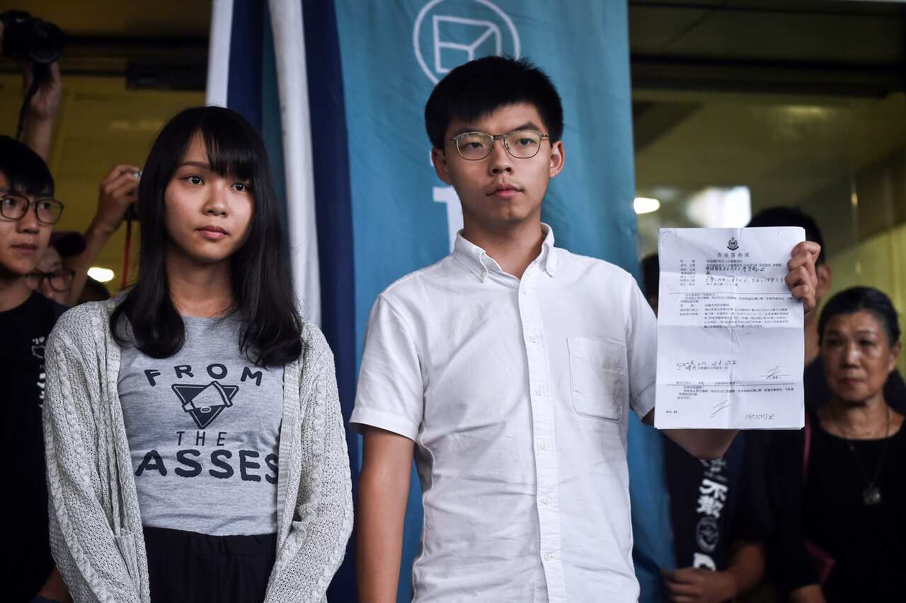 Pro-democracy activists Agnes Chow (L) and Joshua Wong (R) show the charges to the press after they were released on bail at the Eastern Magistrates Courts.