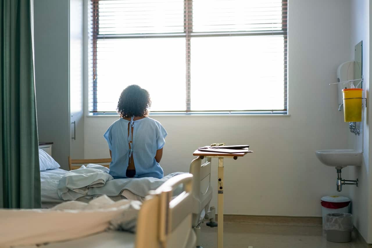 Lonely female patient sitting on hospital bed