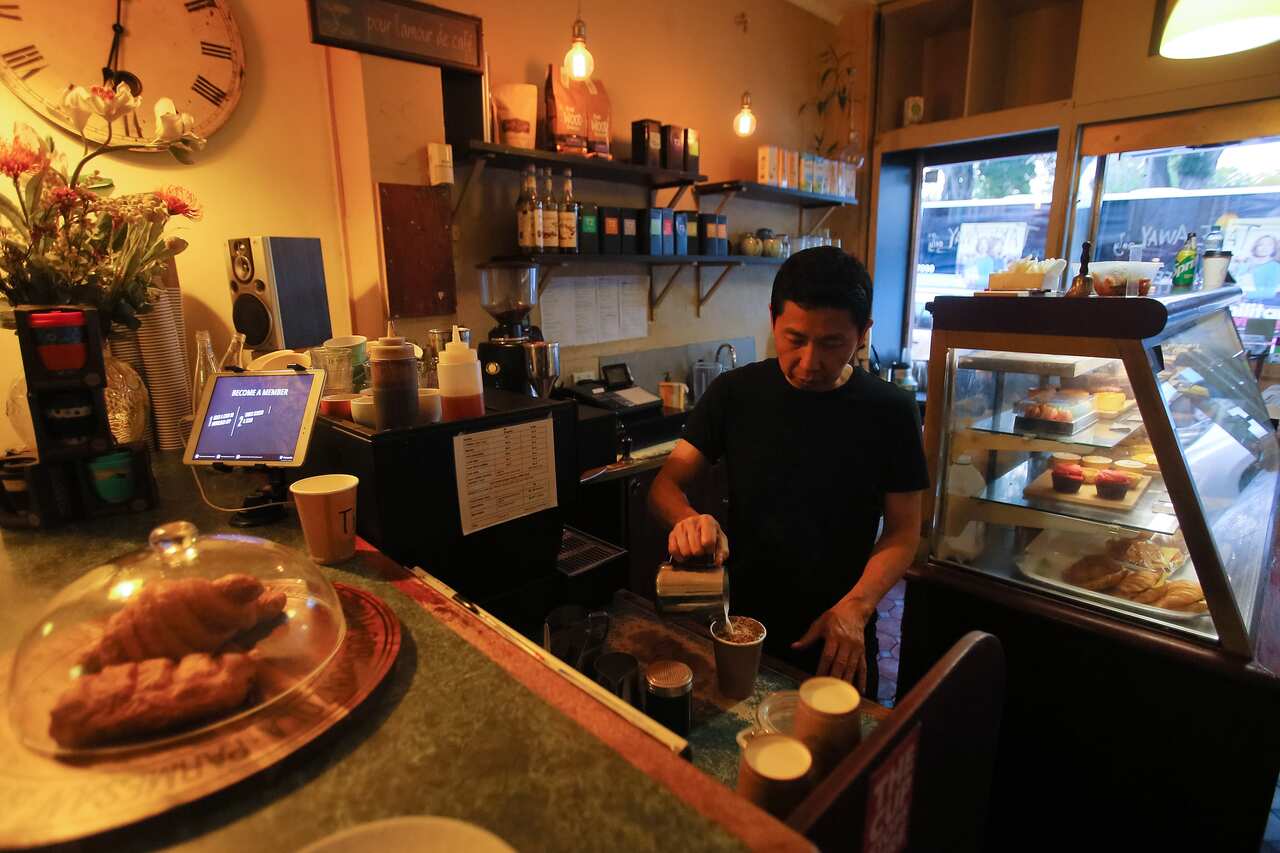 Cafe owner Marc Zheng serves a takeaway coffee at Le Petit Tarte Cafe in Sydney.