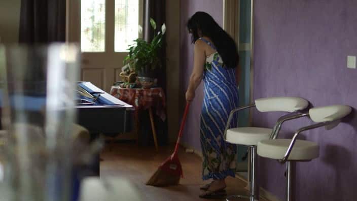 A woman sweeps the floor of a house